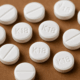 Round K18 white tablets scattered on a flat surface, commonly associated with prescription medications.