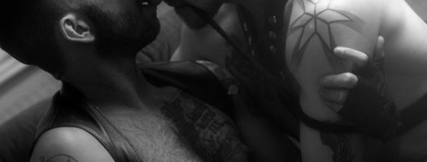 Two gay men in an intimate setting engaging in chemsex, one holding a syringe.