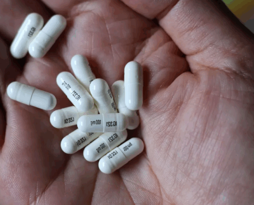 A hand with white gabapentin capsules.