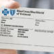 An image of a hand holding Blue Cross Blue Shield insurance card.