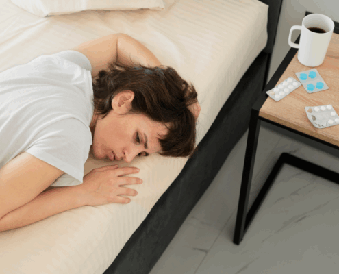 A lesbian woman lying in bed experiencing fatigue and emotional distress.