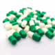 Green-white tramadol capsules scattered on a white surface.