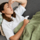 A lesbian woman lying on a couch holding a tissue and looking unwell from klonopin withdrawal.