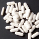 White sedatives capsules scattered on a black surface.