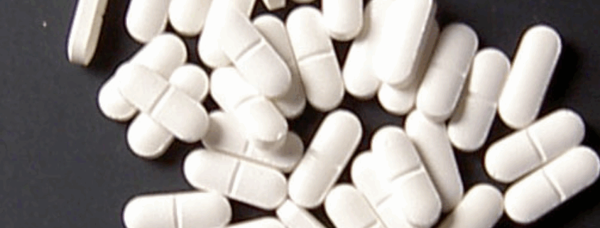 White sedatives capsules scattered on a black surface.