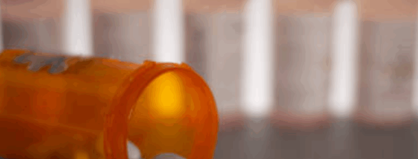 White tranquilizer tablets coming out of a medical bottle.