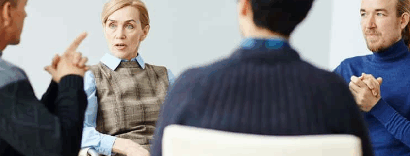 A small group of people at a beginners NA meeting all looking at the person speaking.