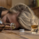 A person lying unconscious on the floor beside an empty bottle, illustrating the dangers of alcohol poisoning