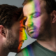 Two men embracing peacefully, with a rainbow light reflection on their faces, symbolizing the benefits of being drug-free.