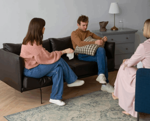 A gay person and two therapists in a trauma therapy session.