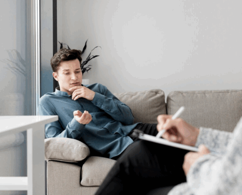 An image of a gay person and a therapist writing on a chart during therapy.