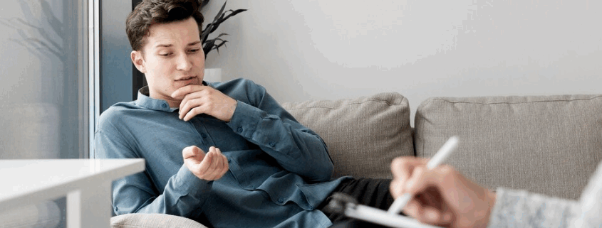 An image of a gay person and a therapist writing on a chart during therapy.