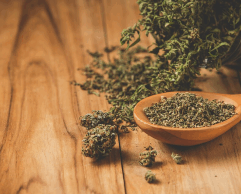 Loose synthetic cannabis (Spice) in a spoon and scattered on a table, representing the dangers of synthetic drug use.