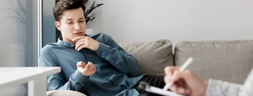 An image of a gay person and a therapist writing on a chart during therapy.