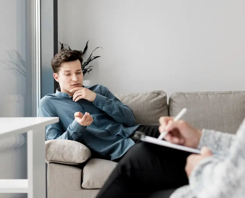 An image of a gay person and a therapist writing on a chart during therapy.