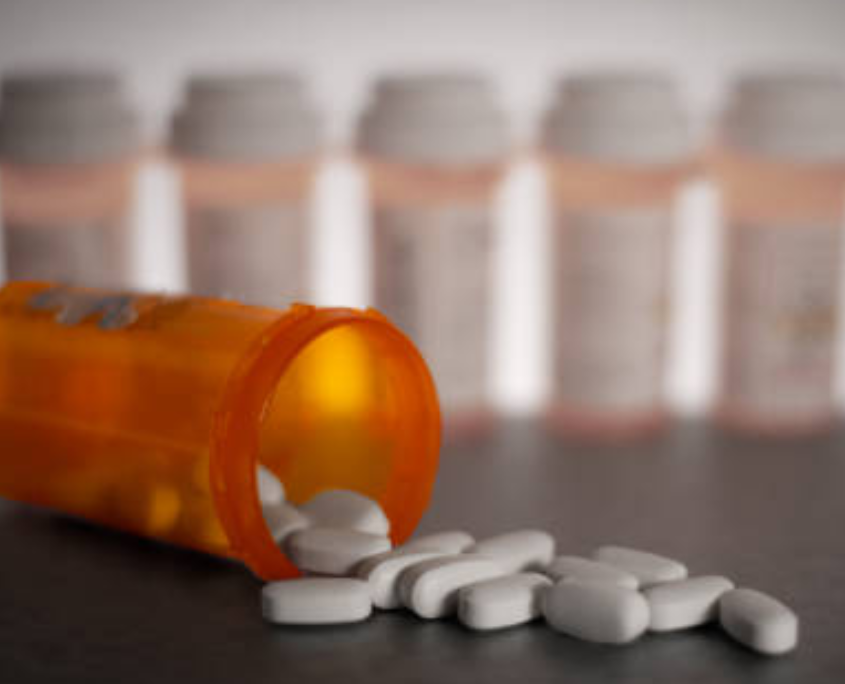 White tranquilizer tablets coming out of a medical bottle.